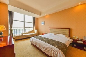 Une chambre d’hôtel avec un lit, un bureau, une chaise, une table de chevet et une fenêtre avec des rideaux.