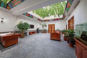 Relax in a spacious room with a high ceiling, featuring a large desk, flat-screen TV, and comfortable seating.