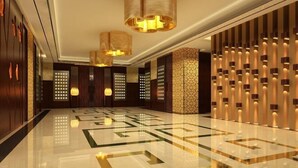 Um hall luxuoso com piso de mármore polido, luminárias elegantes e painéis decorativos na parede.