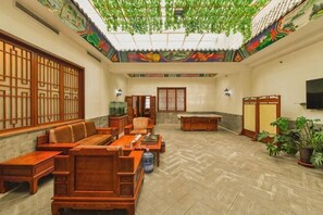 A traditional-style room with a tatami mat floor, a low wooden table, a sofa, a desk, and a television. - Linhai Business Hostel (Luannan)
