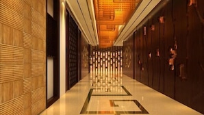 Corredor de hotel moderno com paredes estampadas, design geométrico no chão e teto aconchegante.