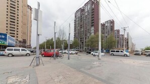 Uma rua com carros estacionados, uma bicicleta e edifícios altos ao fundo.