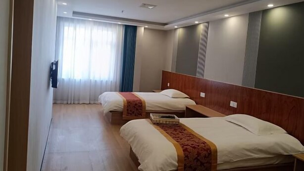 Quarto de hotel com duas camas, cabeceira de madeira, mesa de cabeceira e janela com cortinas.