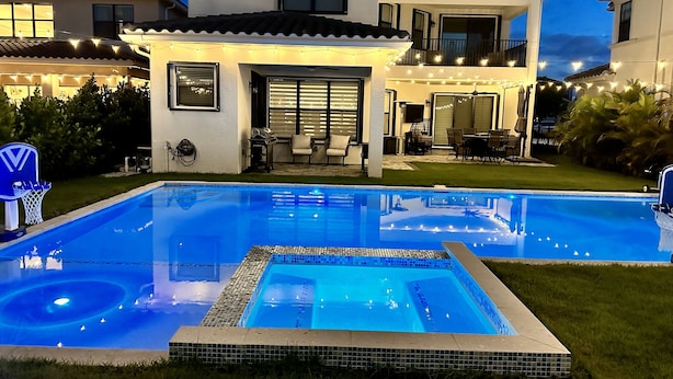 A modern house with a swimming pool, outdoor seating, and string lights.