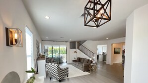 A spacious living area with a modern staircase, a large sofa, and a decorative ceiling light.