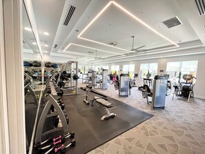 Un gimnasio con diverso equipo de ejercicio, incluyendo cintas de correr, máquinas de pesas y pesas libres.