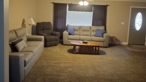 A living room with a beige sofa, a recliner, a coffee table, and a ceiling fan. - short walk to Ball State University Campus - Quiet Neighborhood (Muncie)