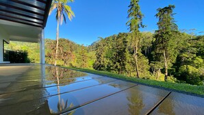 Una terraza moderna al aire libre con vistas despejadas a un bosque exuberante y árboles altos.
