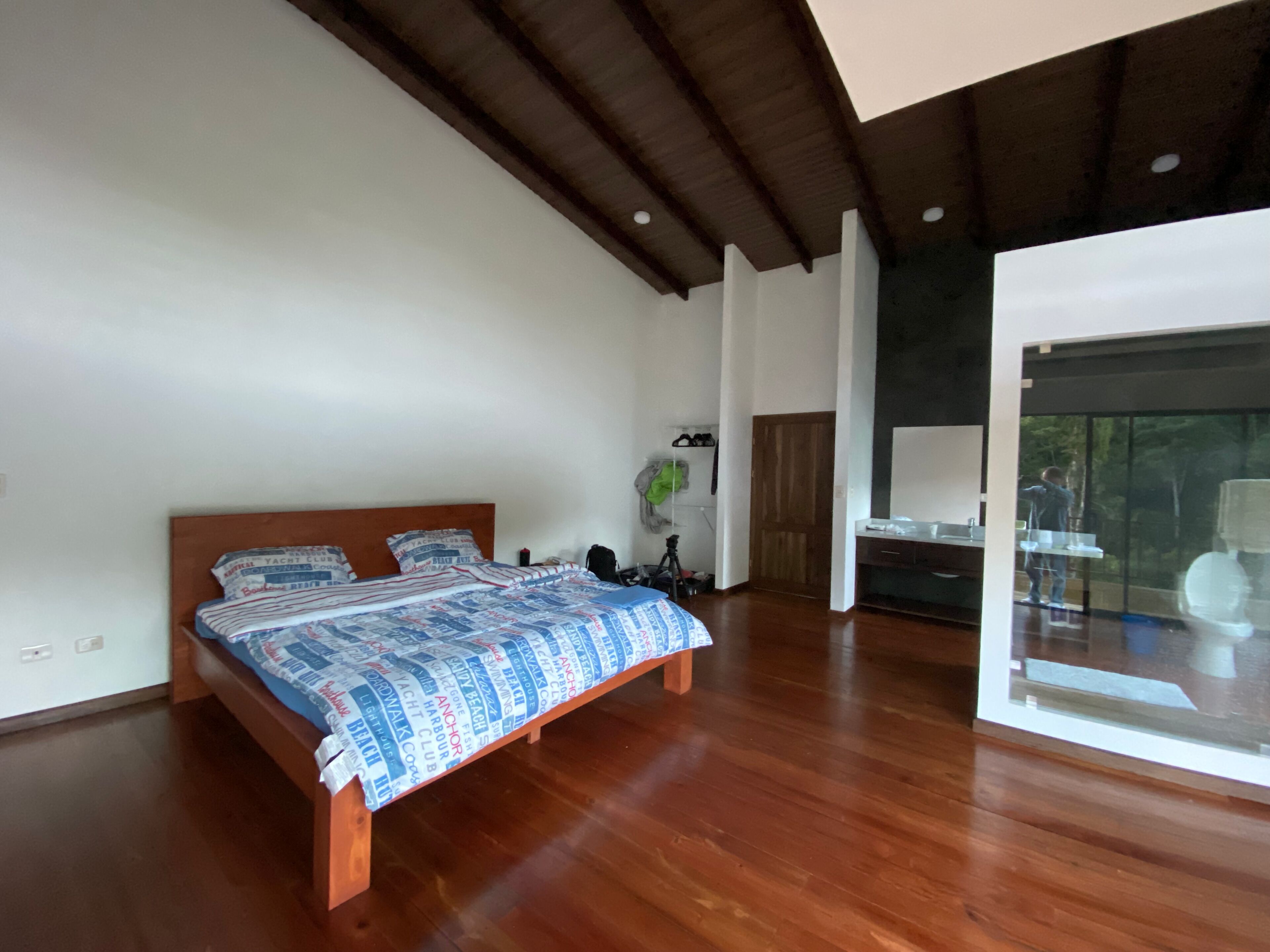Un dormitorio amplio con una cama grande, piso de madera y diseño moderno.