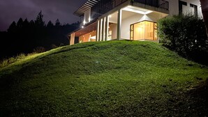 Una casa moderna con balcón, ventanas amplias y un césped bien cuidado.