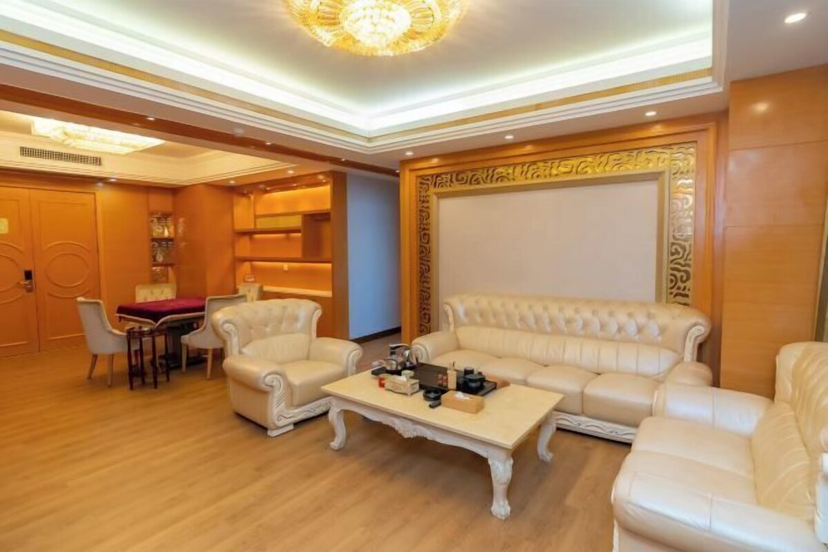 Een ruime woonkamer met een grote beige bank, een salontafel en een eethoek met een tafel en stoelen.