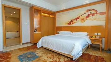 A hotel room with a bed, a nightstand, a wall-mounted TV, and a door leading to a bathroom.