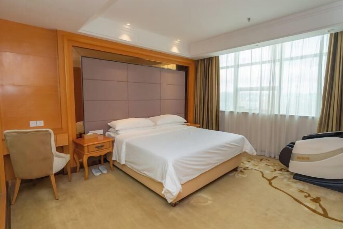 Een hotelkamer met een bed, een bureau, een stoel en een massagestoel.