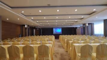 A conference room with rows of tables and chairs, a projection screen, and a carpeted floor.
