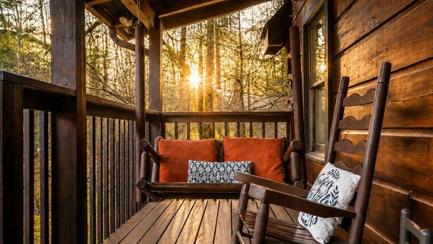 A wooden deck with a bench and pillows, surrounded by bamboo. - Cozy Cabin- 5mins From Pigeon Forge - Hot Tub (Pigeon Forge)