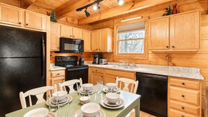 A wooden cabin-style kitchen with a black refrigerator, microwave, stove, and dishwasher. - Cozy Cabin- 5mins From Pigeon Forge - Hot Tub (Pigeon Forge)