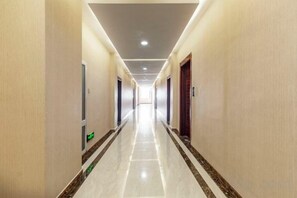 A long, narrow hotel corridor with doors on both sides, a tiled floor, and a ceiling with recessed lighting. - Jinjiang International Hotel (Shangdu)