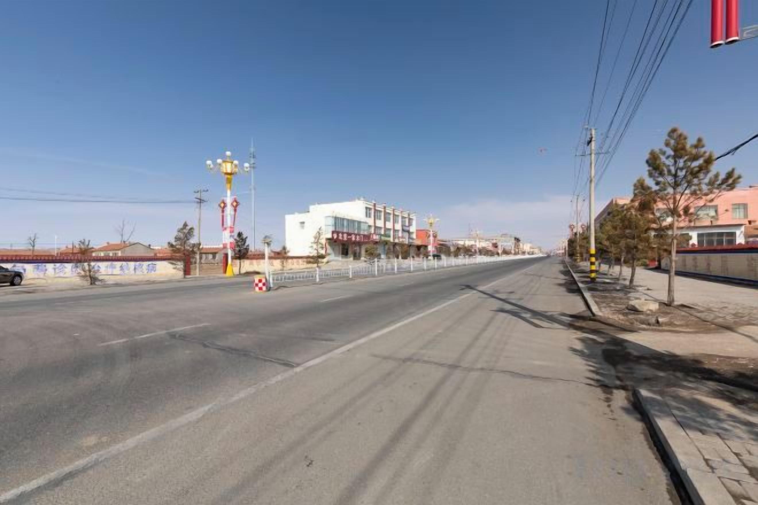 A wide road with a pedestrian crossing and a building in the background.