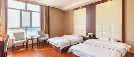 Een hotelkamer met twee bedden, een bureau, stoelen en een groot raam.