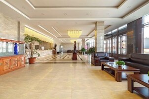 A spacious lobby with a reception desk, seating area, and large windows.