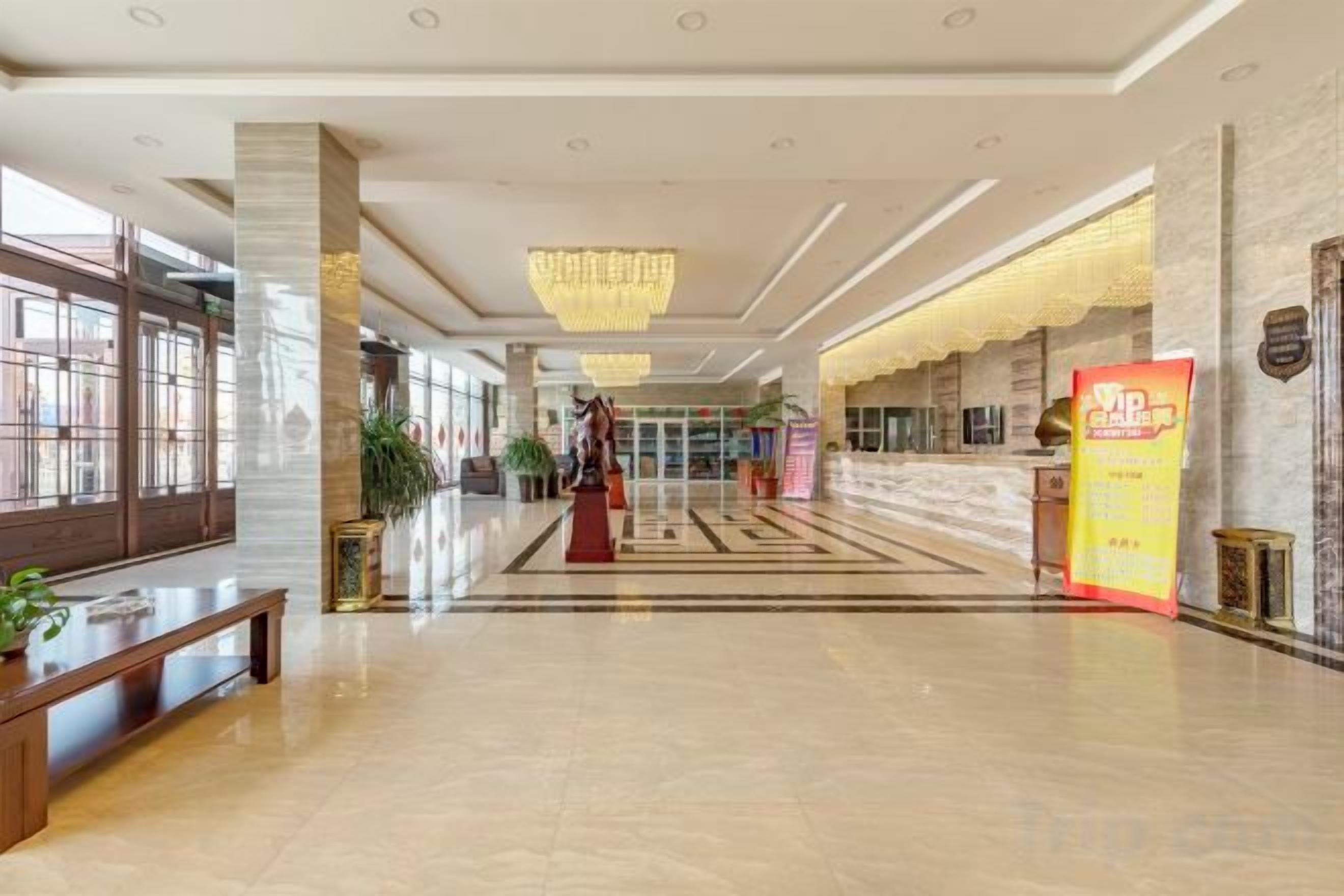 A spacious lobby with a reception desk, a chandelier, and a check-in counter.