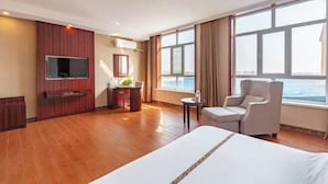 A hotel room with a large bed, a desk, a chair, a television, and a window with a view.