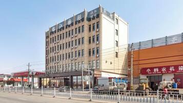 A multi-story hotel with a flat facade, a ground-level entrance, and a visible storefront on the right.