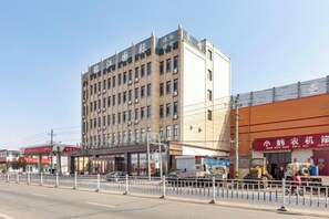 A multi-story hotel with a flat facade, a ground-level entrance, and a visible storefront on the right. - Jinjiang International Hotel (Shangdu)