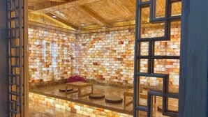 A room with a wooden ceiling and walls made of multicolored tiles. There is a seating area with a table and chairs.