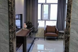 A modern hotel room with a large window, a desk with a chair, a sofa, and a small side table. - Jinjiang International Hotel (Shangdu)