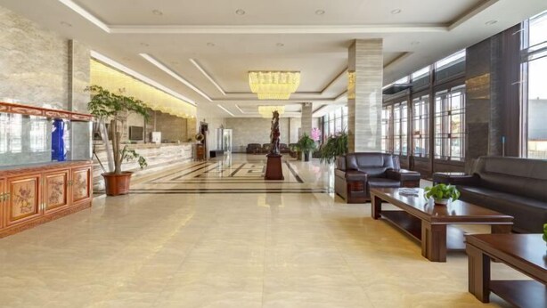 A spacious lobby with a marble floor, a large chandelier, and a seating area with sofas and a coffee table.