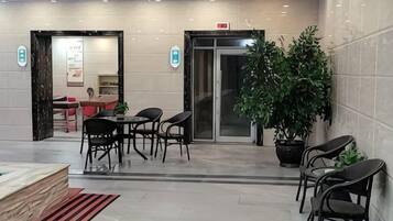 Un vestíbulo de hotel con mostrador de recepción, zona de estar y una planta en maceta.