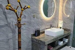 Une salle de bain moderne avec un meuble-lavabo en marbre, un grand miroir et une structure décorative en bois.