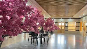 A lobby with a reception desk, seating area, and a decorative artificial cherry blossom tree.