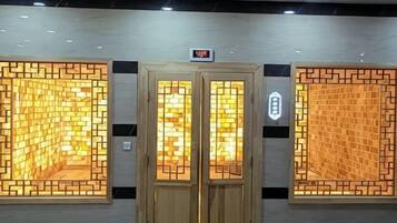 Entrada de hotel con puerta de madera y dos paneles iluminados en la pared.