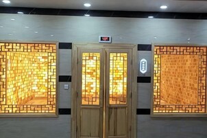 A hotel entrance with a wooden door and two illuminated wall panels.