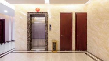 An elevator, two doors, and a marble floor in a hallway.