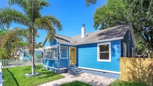 A small, single-story house with a blue exterior, a yellow front door, and a visible chimney. - The Blue Bungalow by Crescent Lake Walk 2 Downtown K&Q Hot Tub Private Courtyard (St. Petersburg)