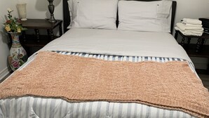 A bed with a striped bedspread, a vase with flowers, a lamp, and a painting on the wall. - Cozy and quite 2 bedroom basement appartment with separate entrance… (Mississauga)