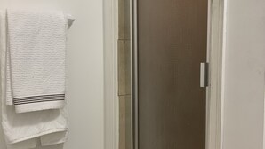 A bathroom with a shower door, a towel rack with a folded towel, and a tiled floor. - Cozy and quite 2 bedroom basement appartment with separate entrance… (Mississauga)