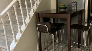 A small kitchen with a dining table and two chairs, a refrigerator, and a white staircase. - Cozy and quite 2 bedroom basement appartment with separate entrance… (Mississauga)