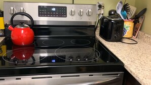 A kitchen with a stainless steel stove, a red kettle, and a toaster on the countertop. - Cozy and quite 2 bedroom basement appartment with separate entrance… (Mississauga)
