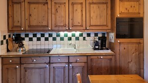 Une cuisine avec des meubles en bois, un pare-feu en carreaux et un plan de travail sur lequel se trouvent divers appareils électroménagers.