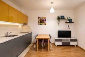 Moderni keittiö, jossa on ruokailutila, televisio ja huonekasvi.