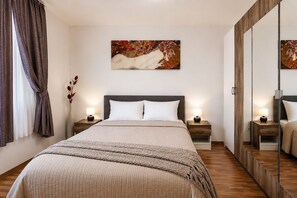 A hotel room with a large bed, two bedside tables with lamps, a mirror, and a painting on the wall.