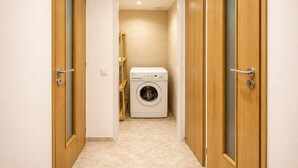 A laundry room with a washing machine, wooden doors, and tiled flooring. - Ground Floor Apartment (Prague)
