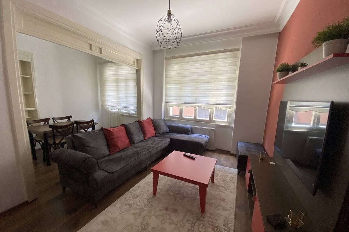A living room with a sofa, a coffee table, a TV, and a dining area with chairs and a table.