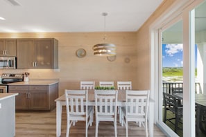 A modern kitchen with wooden cabinets, a stainless steel microwave, and a hanging light fixture.