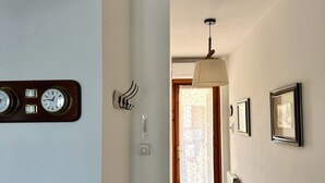 A hallway with a wooden door, a radiator, and wall-mounted clocks. - M324 - Marcelli, delightful three-room apartment with panoramic terrace (Marcelli)