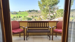 A balcony with a wooden bench and two chairs, a yellow wall, and a view of a green landscape. - M324 - Marcelli, delightful three-room apartment with panoramic terrace (Marcelli)